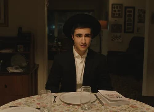 A young man in traditional dress seated at a dining table